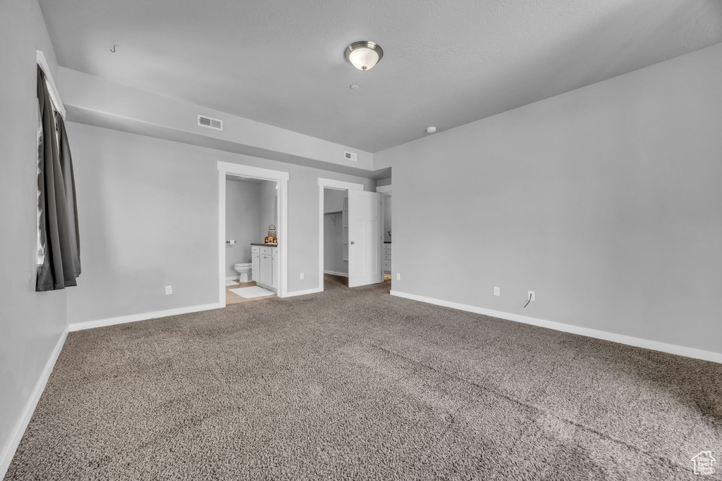 Unfurnished bedroom featuring baseboards, connected bathroom, visible vents, and carpet floors