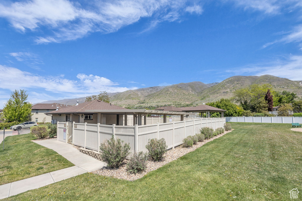 View of property exterior featuring a mountain view, fence, and a lawn