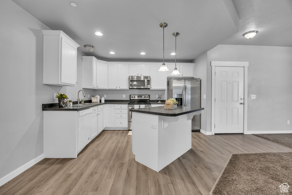 Kitchen with baseboards, light wood-style flooring, appliances with stainless steel finishes, and white cabinets