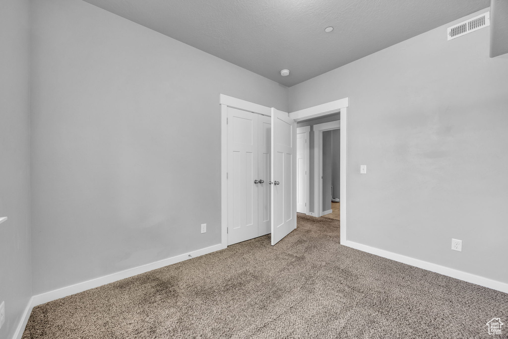Unfurnished bedroom with baseboards, a closet, visible vents, and carpet floors