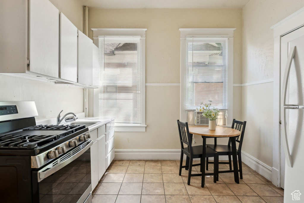 Kitchen with white cabinetry, stainless steel range with gas stovetop, baseboards, and a sink