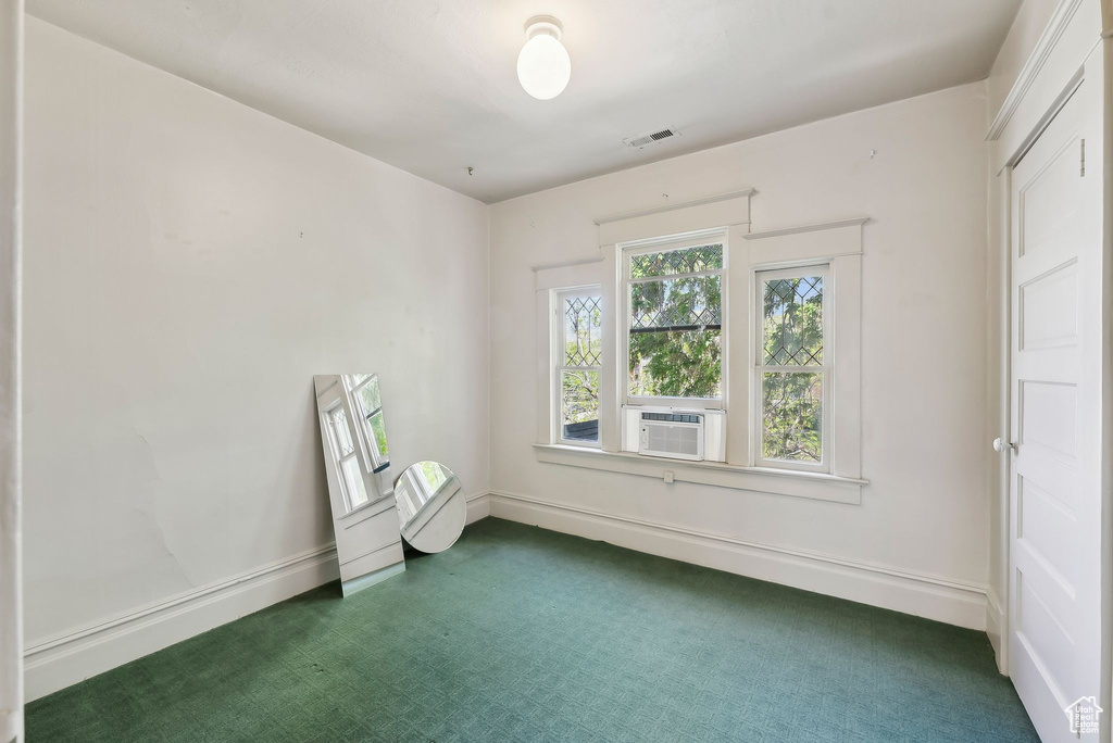 Unfurnished room featuring cooling unit, baseboards, and dark carpet