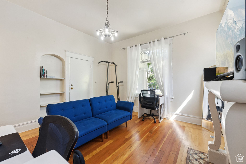Living room with baseboards, a notable chandelier, and light wood-style floors