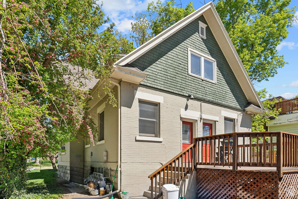 Back of property featuring brick siding, a deck, and a garage