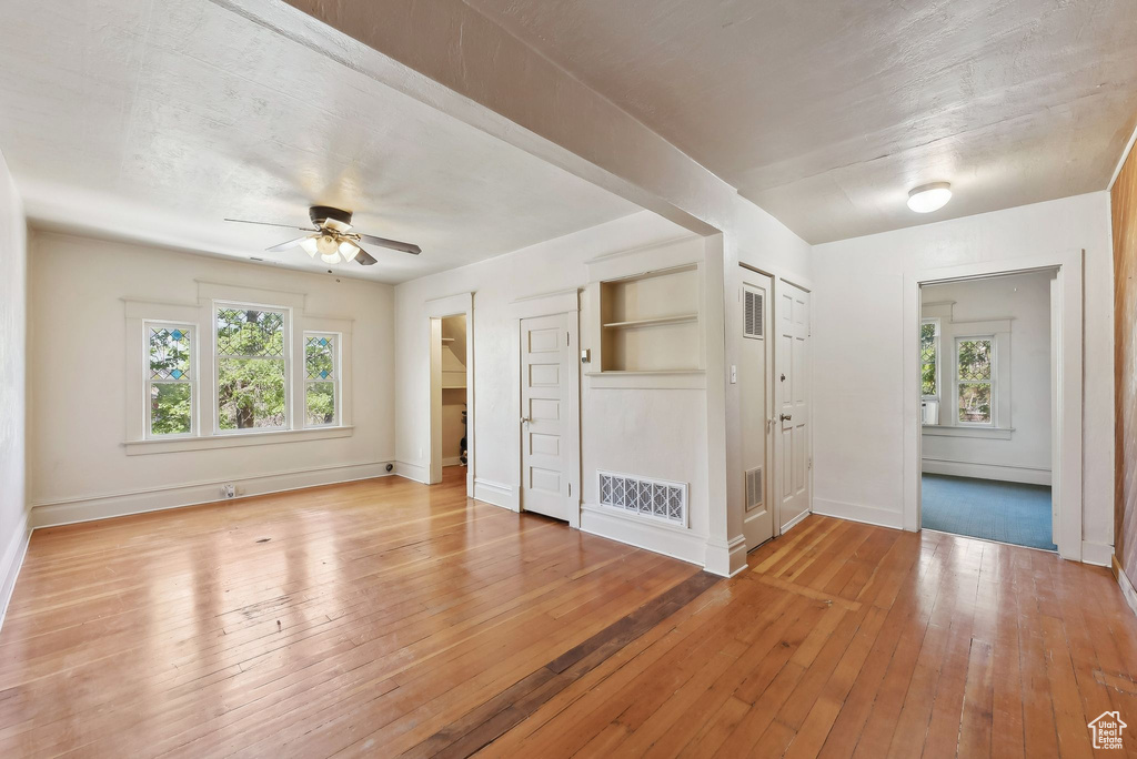 Interior space with multiple windows, light wood-style floors, visible vents, and baseboards