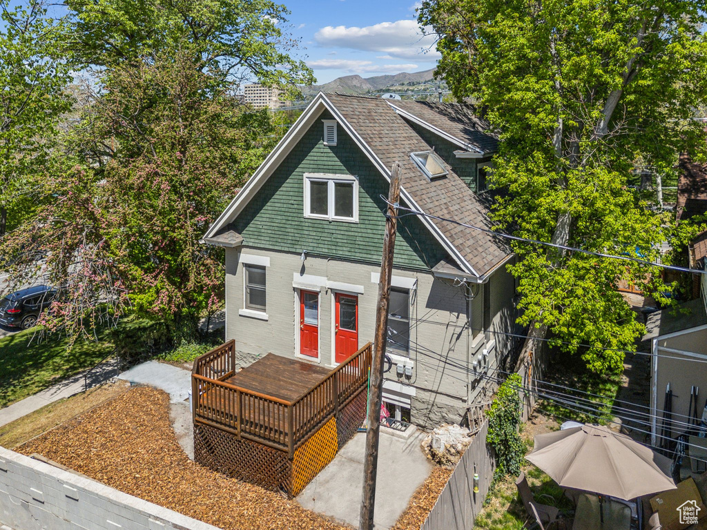 View of front of house with brick siding, a deck with mountain view, and fence