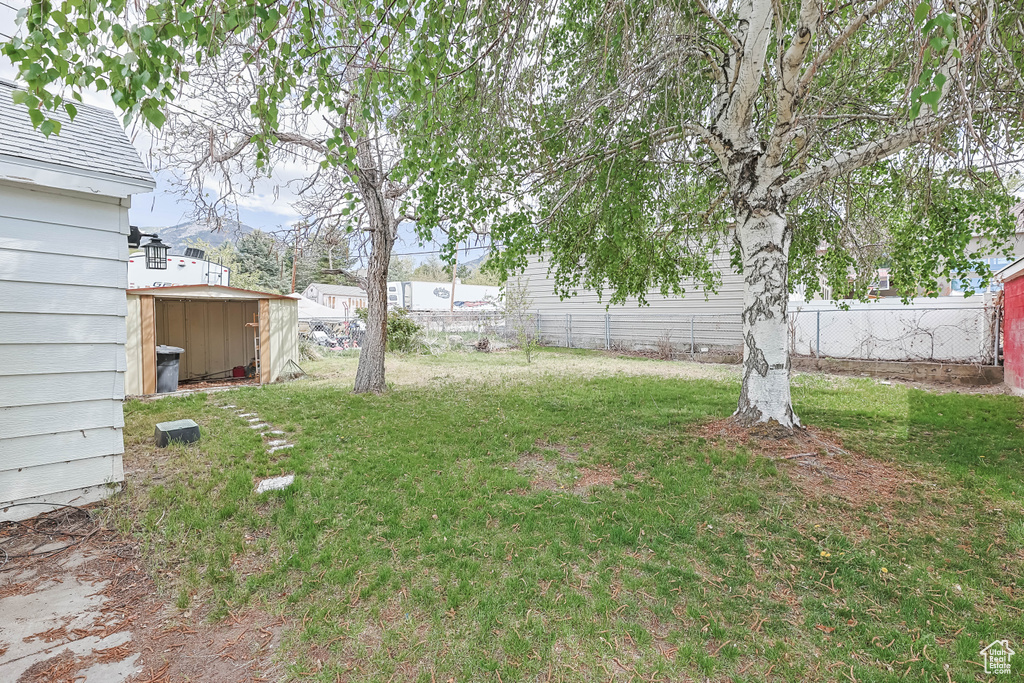 View of yard featuring a storage unit, fence, and an outbuilding