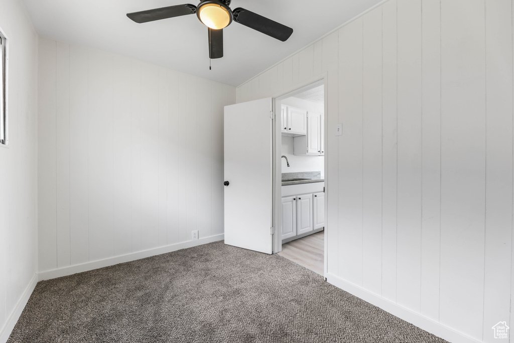Unfurnished bedroom with a sink, light colored carpet, connected bathroom, and a ceiling fan