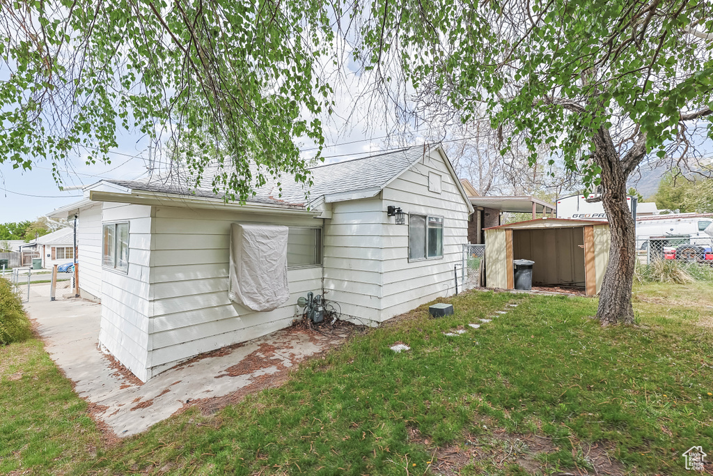 Back of house featuring fence, an outdoor structure, a shed, and a lawn