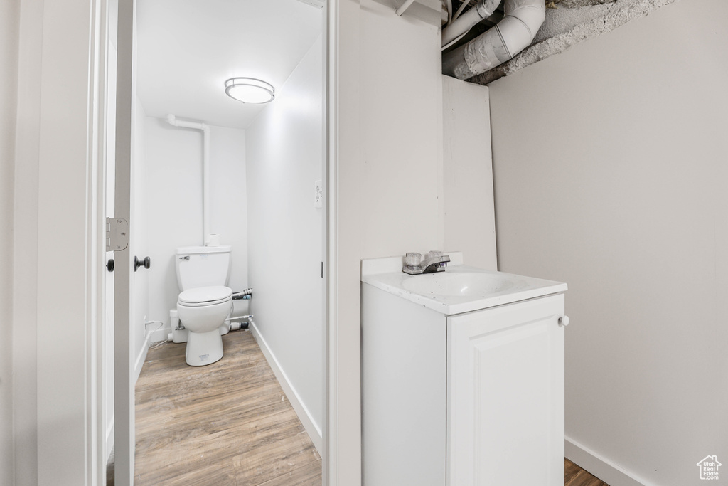 Half bath featuring toilet, baseboards, vanity, and wood finished floors