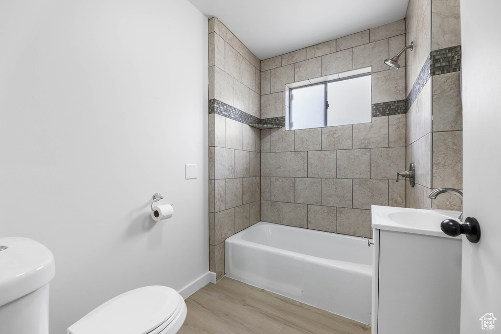 Full bath featuring toilet, wood finished floors, vanity, baseboards, and bathtub / shower combination