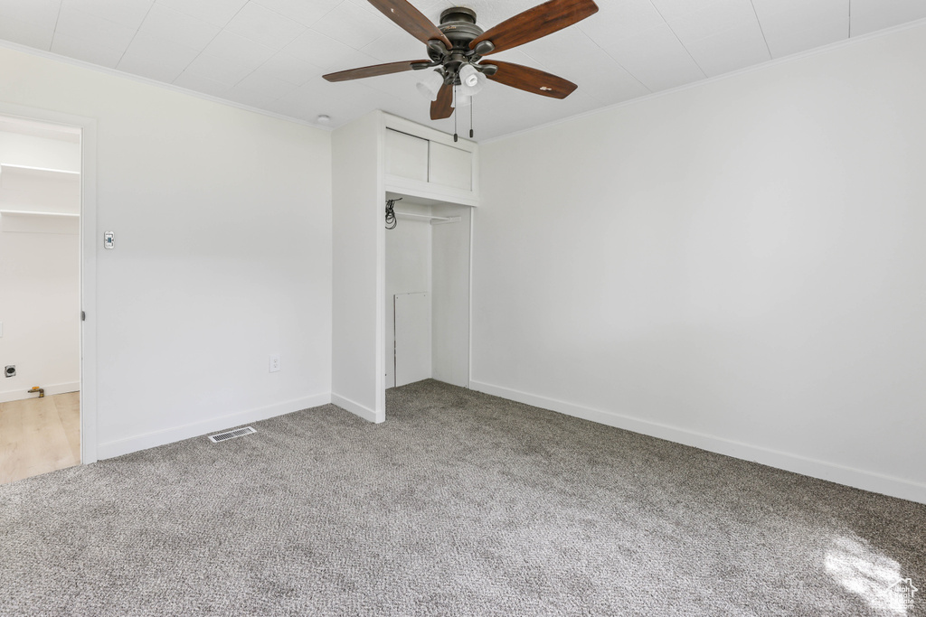 Unfurnished bedroom with a closet, carpet, baseboards, visible vents, and crown molding