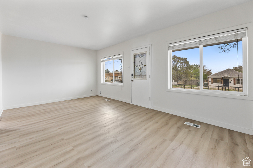 Spare room featuring light wood finished floors, visible vents, and baseboards
