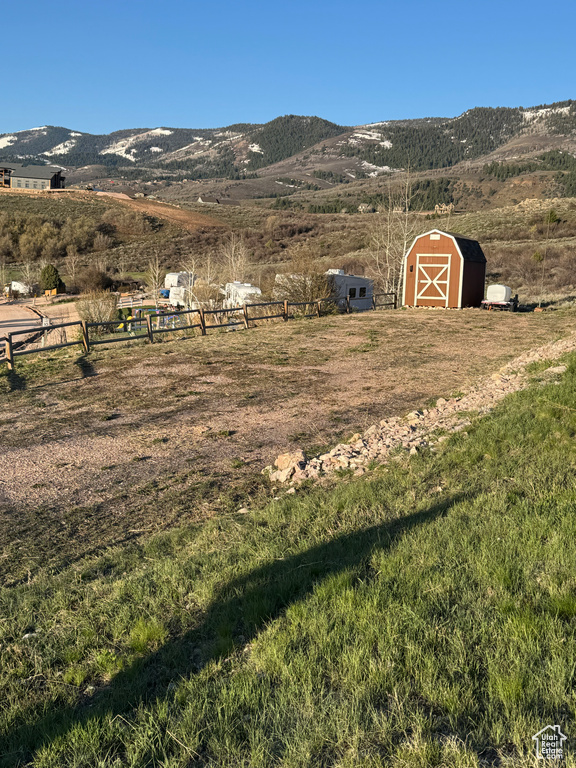 View of yard featuring a storage unit, a rural view, a mountain view, and an outbuilding