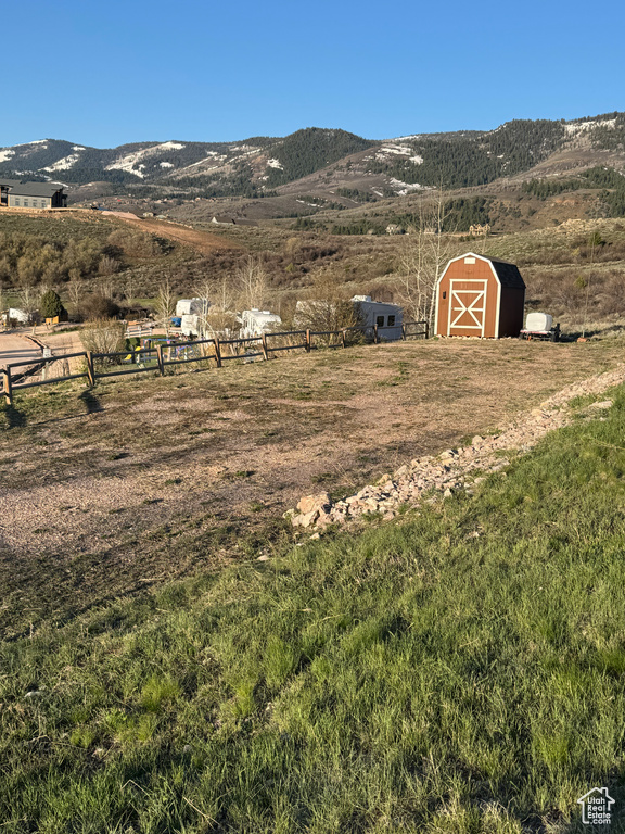 Exterior space with fence, a mountain view, a storage unit, an outbuilding, and a rural view