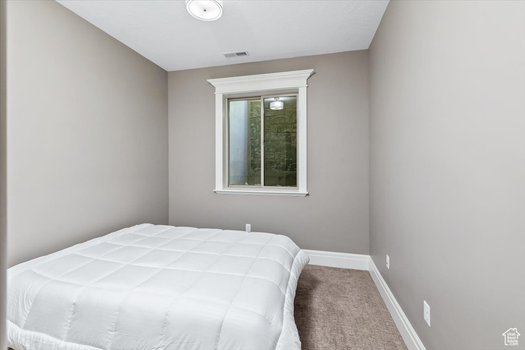 Carpeted bedroom featuring baseboards and visible vents