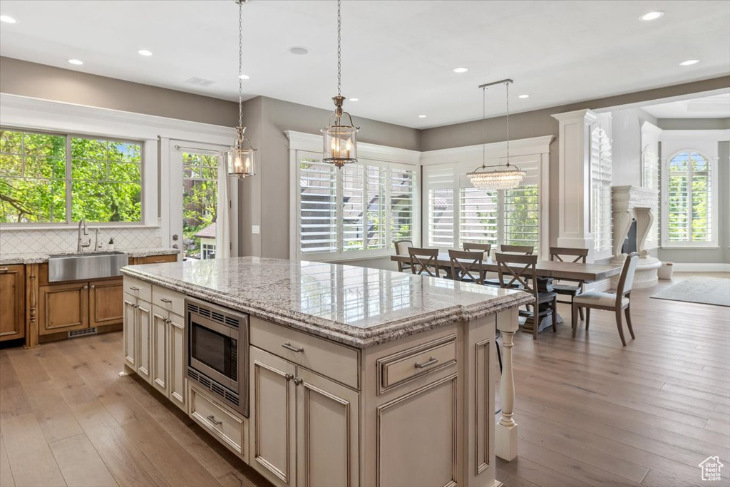 Kitchen with light wood-type flooring, a kitchen island, stainless steel microwave, and a sink