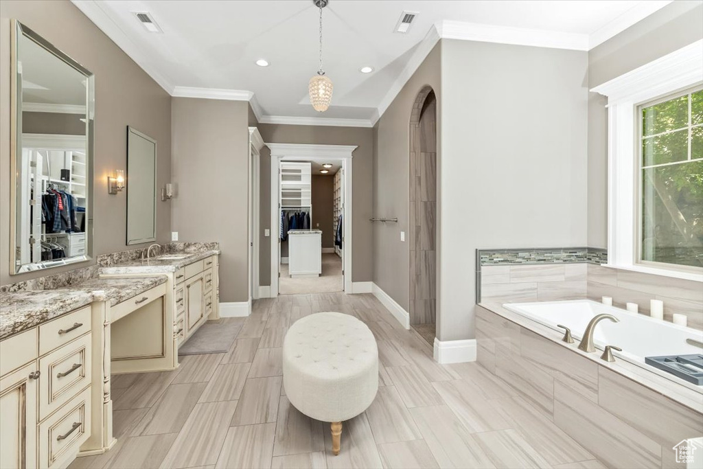 Full bathroom featuring a garden tub, vanity, a walk in closet, and crown molding