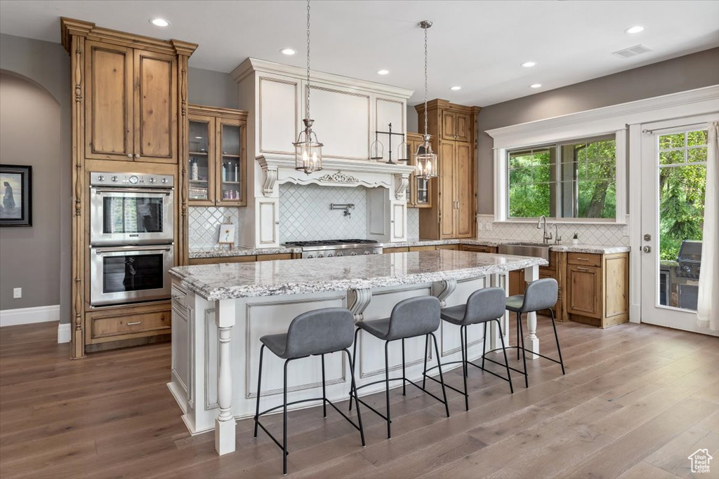 Kitchen featuring brown cabinets, a center island, light wood-type flooring, and stainless steel double oven