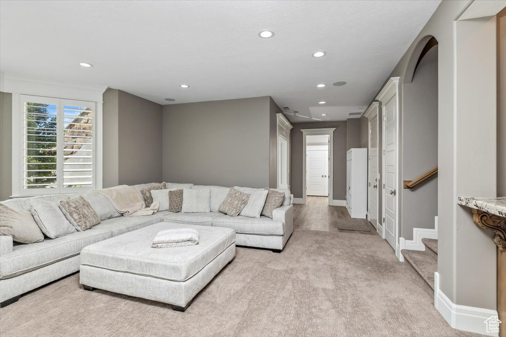 Living area with baseboards, light carpet, recessed lighting, and stairway