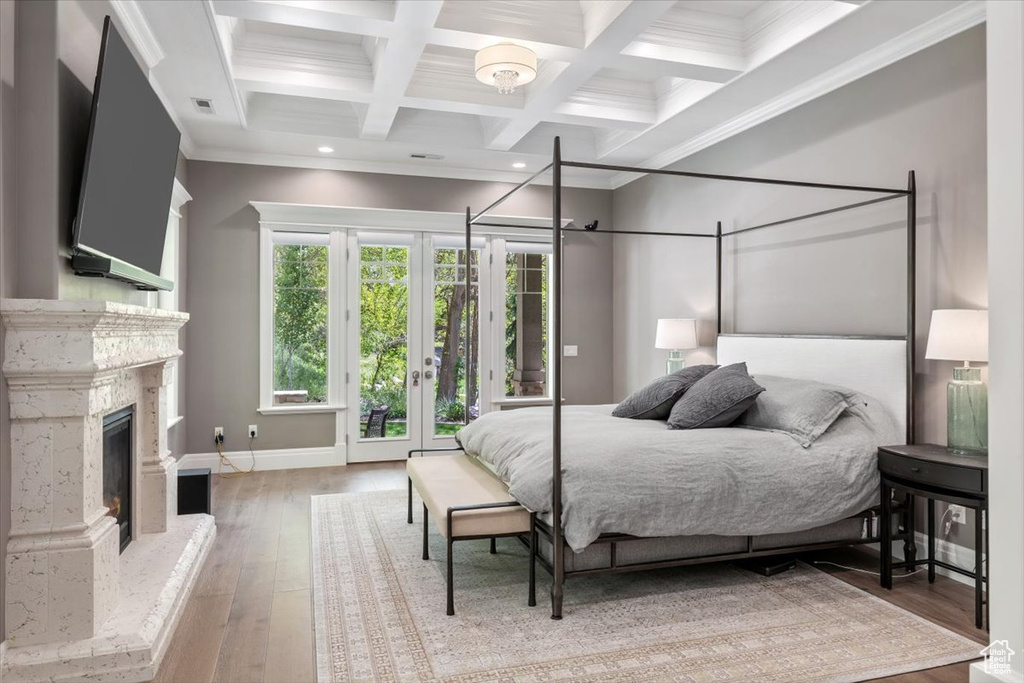 Bedroom with french doors, wood-type flooring, coffered ceiling, beam ceiling, and a high end fireplace