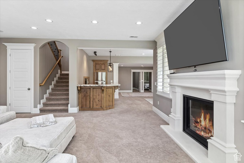 Living room with recessed lighting, visible vents, light carpet, and a glass covered fireplace