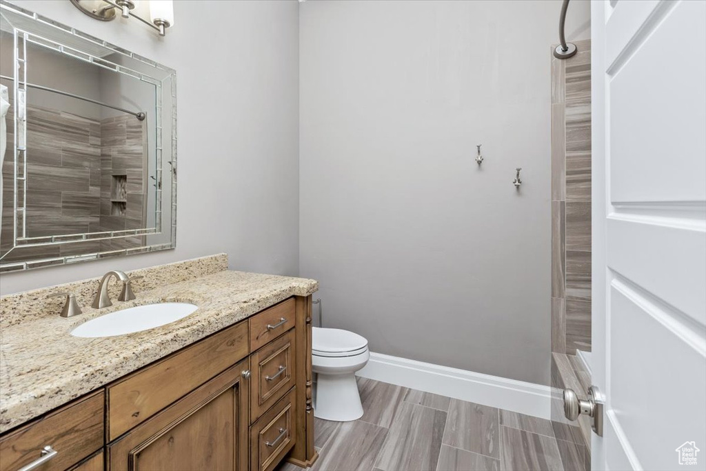 Bathroom with vanity, toilet, baseboards, and tiled shower