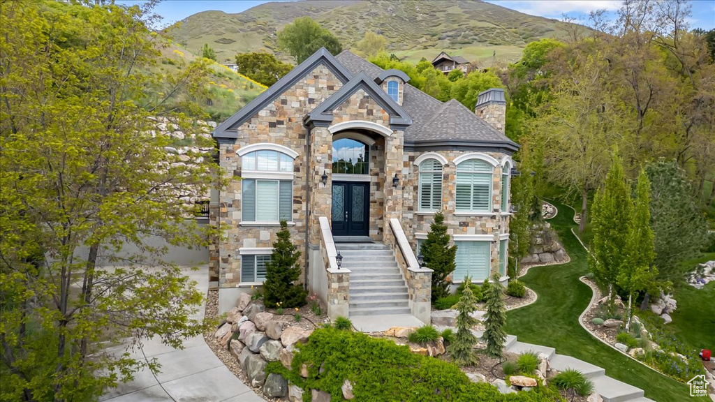 View of front of house with a mountain view, a chimney, french doors, and stone siding