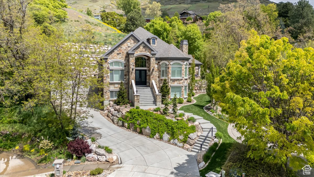 View of front of property featuring stone siding, stairway, and a chimney