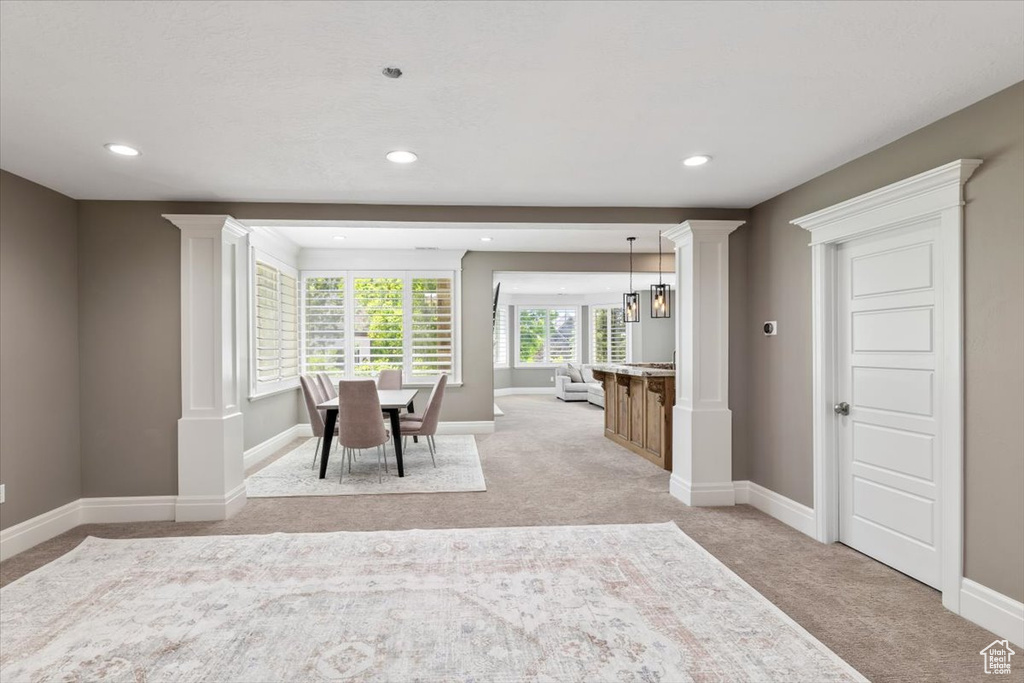 Dining room featuring light carpet, baseboards, and decorative columns