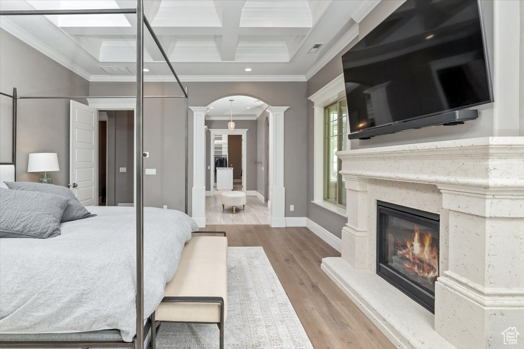 Bedroom featuring coffered ceiling, baseboards, ornamental molding, decorative columns, and arched walkways
