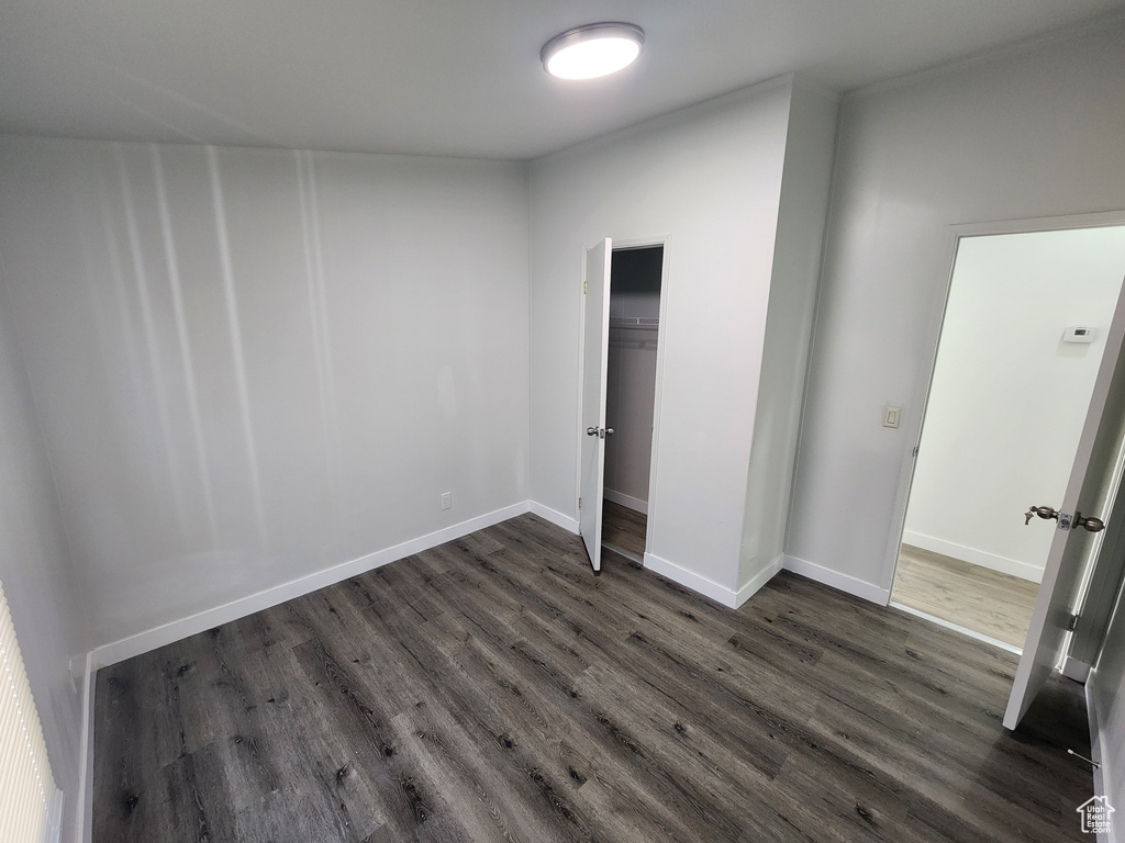 Unfurnished bedroom with baseboards and dark wood finished floors