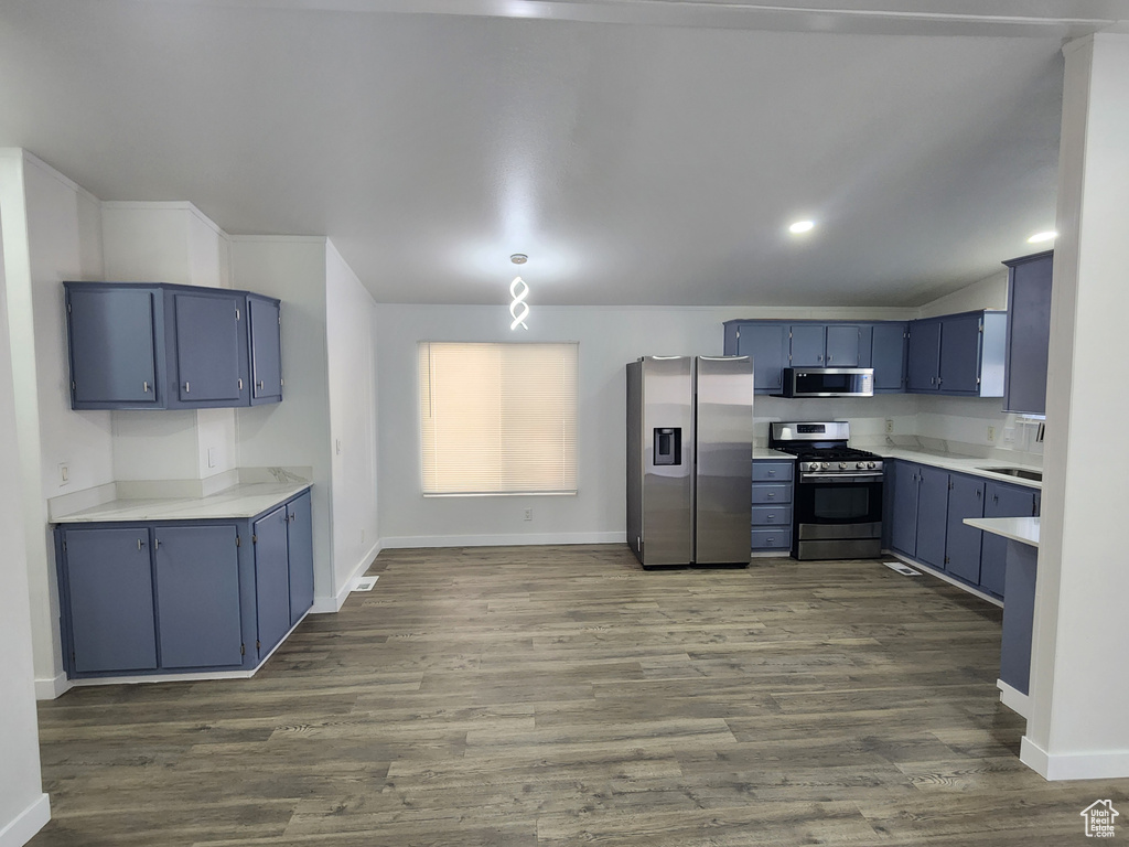 Kitchen featuring light countertops, dark wood-style floors, blue cabinetry, baseboards, and appliances with stainless steel finishes