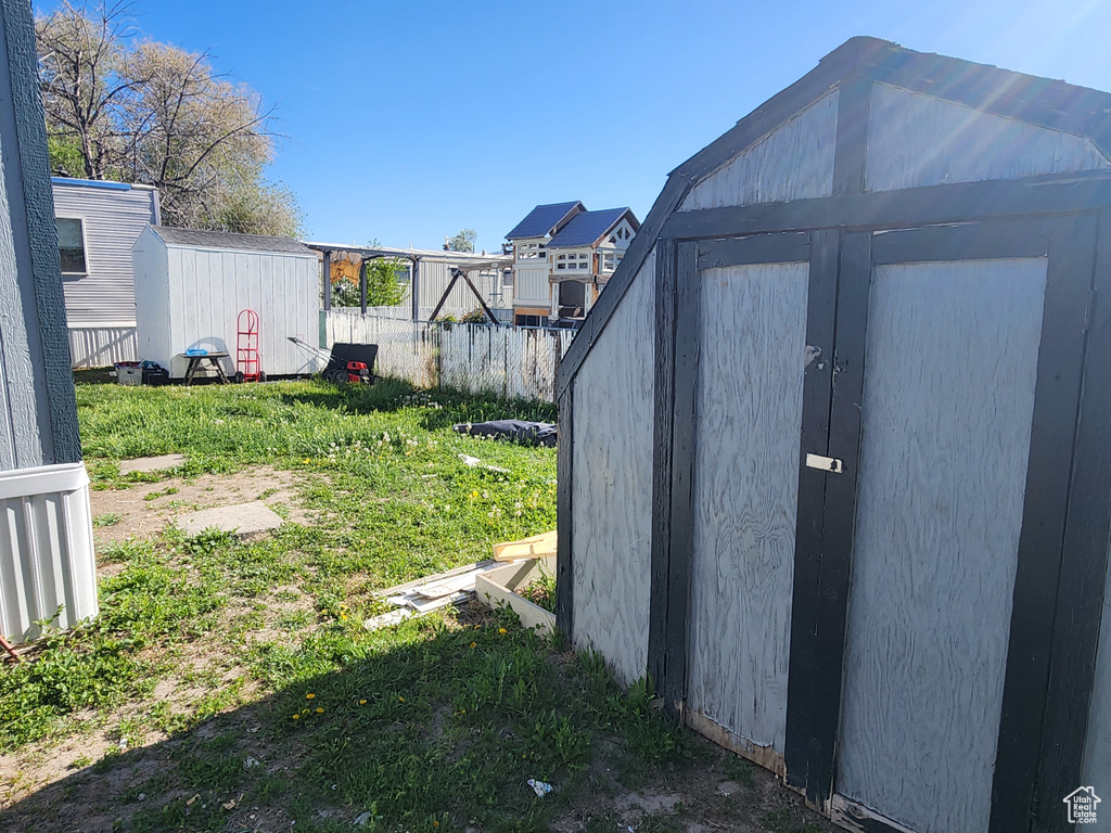 View of yard featuring a storage shed, an outbuilding, and fence