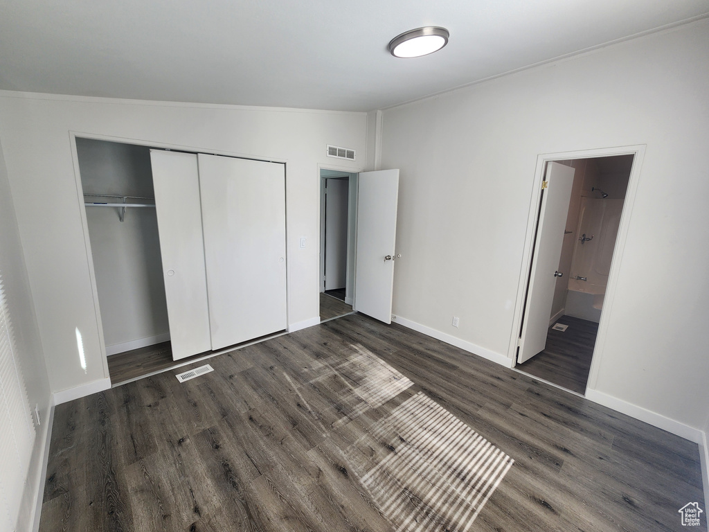 Unfurnished bedroom featuring baseboards, a closet, dark wood-style floors, and visible vents