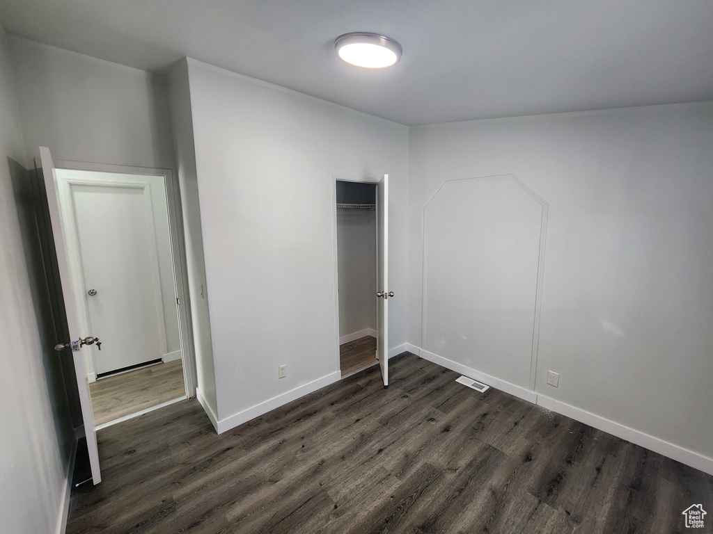 Unfurnished bedroom with baseboards, a closet, visible vents, and dark wood-type flooring
