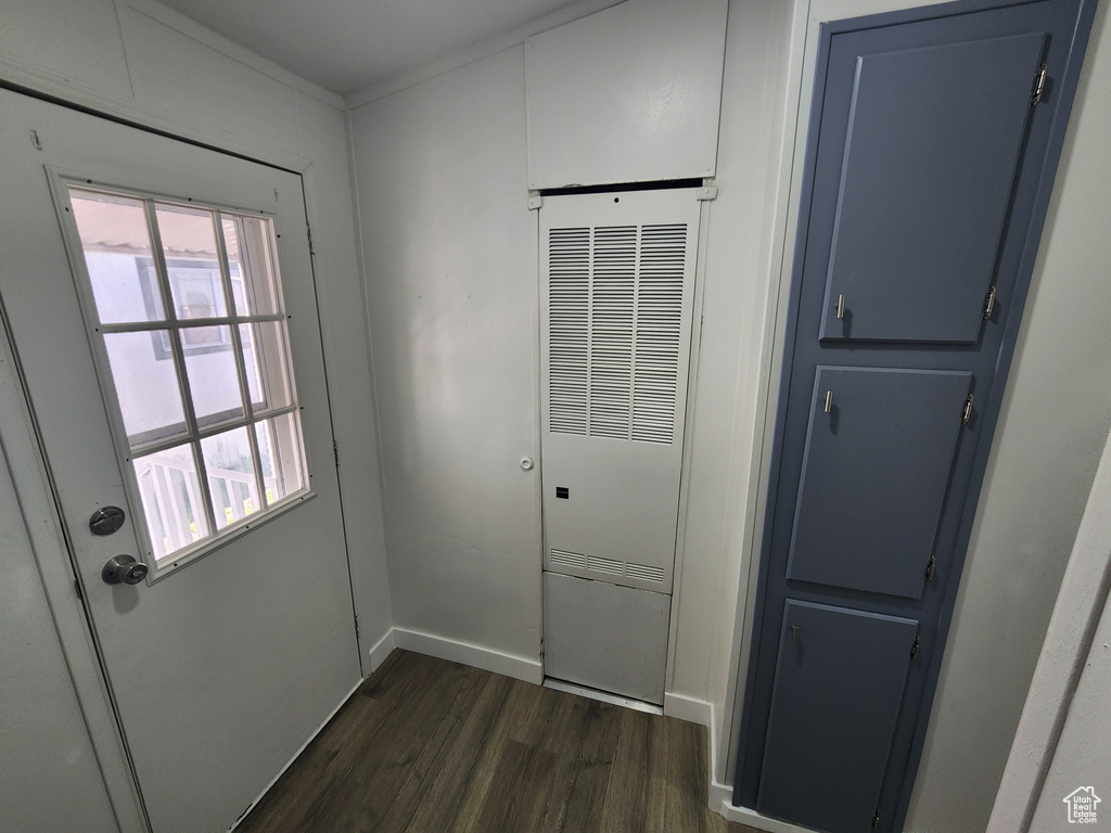 Doorway featuring baseboards, a heating unit, and dark wood finished floors