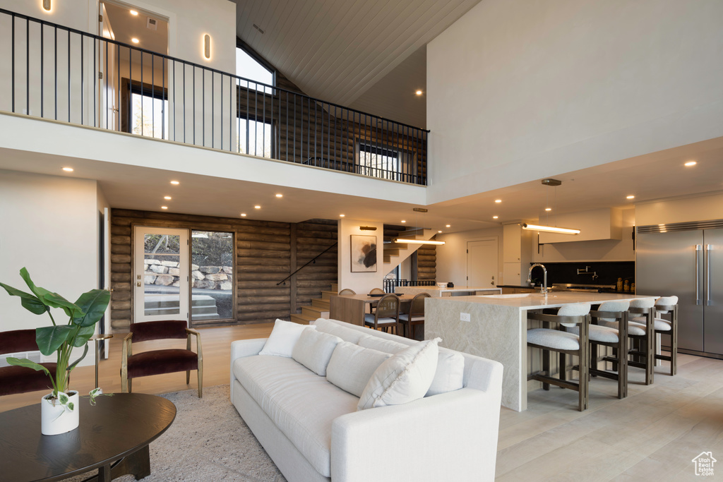 Living room with log walls, high vaulted ceiling, a healthy amount of sunlight, and stairs