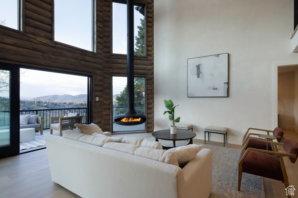 Living room with a mountain view, log walls, a towering ceiling, wood finished floors, and a wood stove