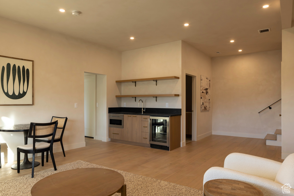 Living area with wine cooler, recessed lighting, visible vents, wet bar, and light wood-type flooring