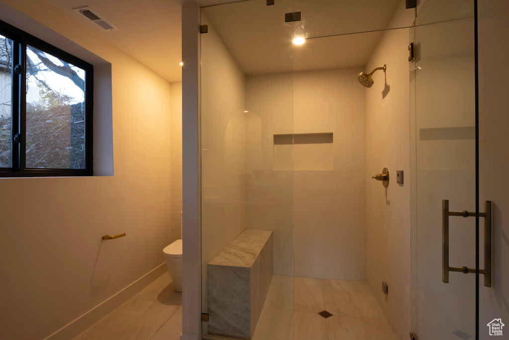 Full bathroom featuring toilet, tile patterned flooring, visible vents, and a shower stall