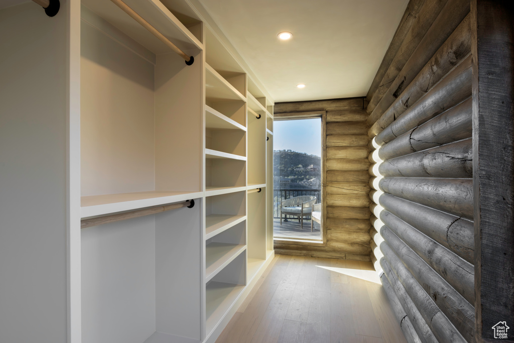 Walk in closet with hardwood / wood-style floors