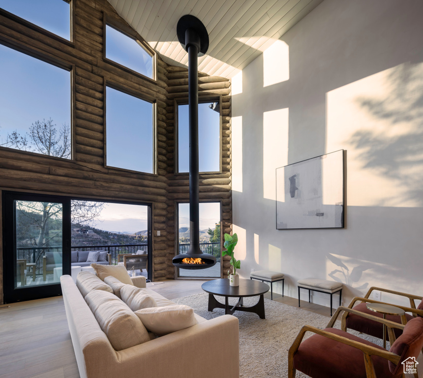 Living area with a wood stove, log walls, high vaulted ceiling, and wooden ceiling