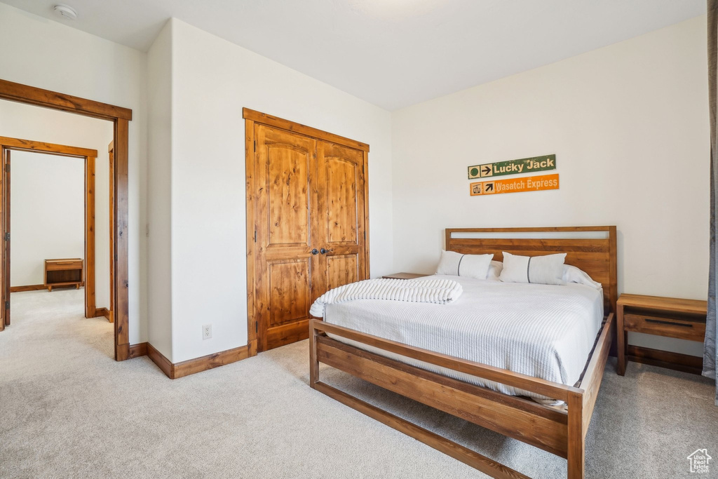 Bedroom with light colored carpet, baseboards, and a closet