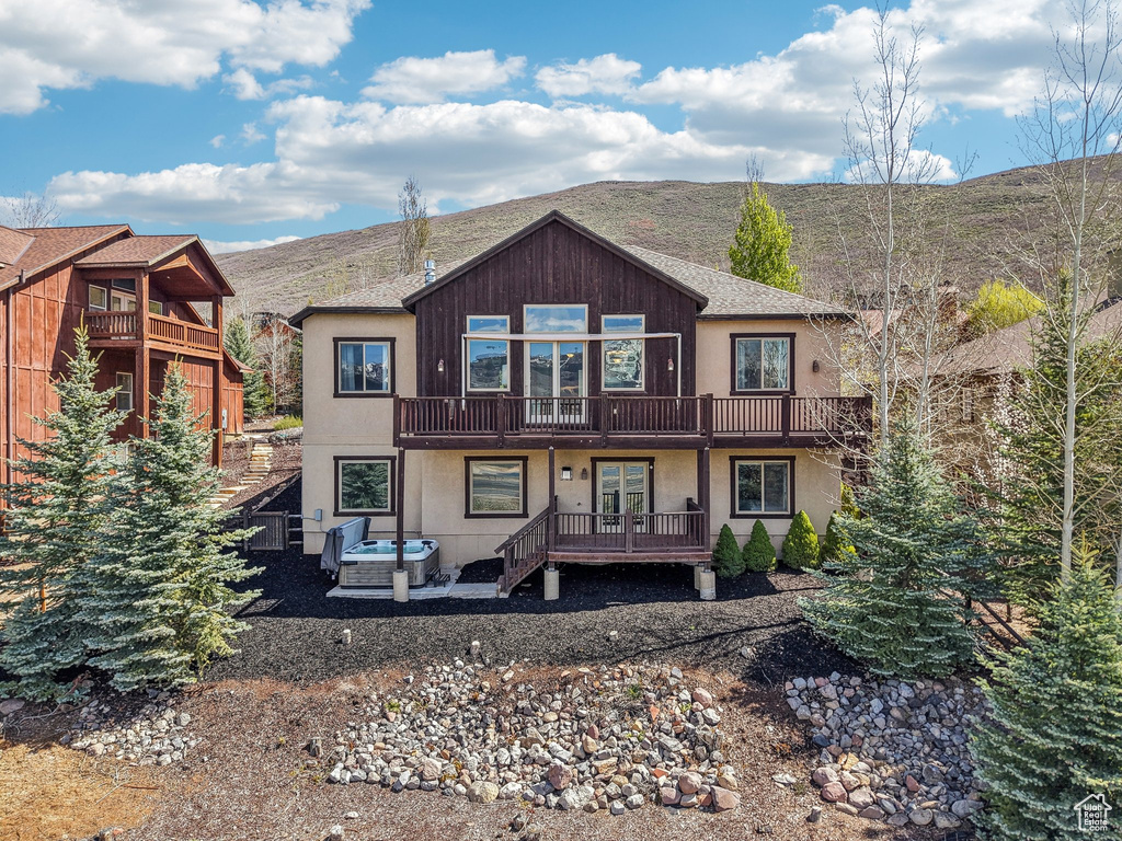 Back of house with a deck, a patio, stucco siding, and french doors