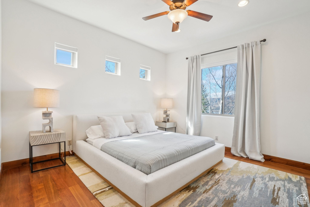 Bedroom featuring baseboards, multiple windows, and wood finished floors