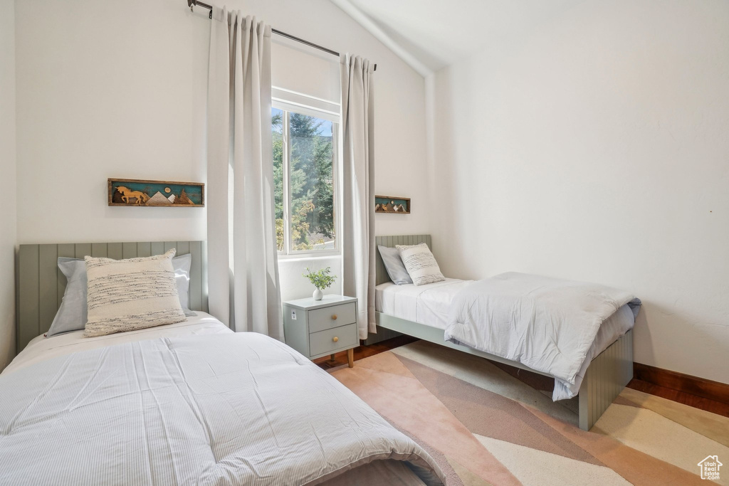 Bedroom featuring baseboards, wood finished floors, and lofted ceiling