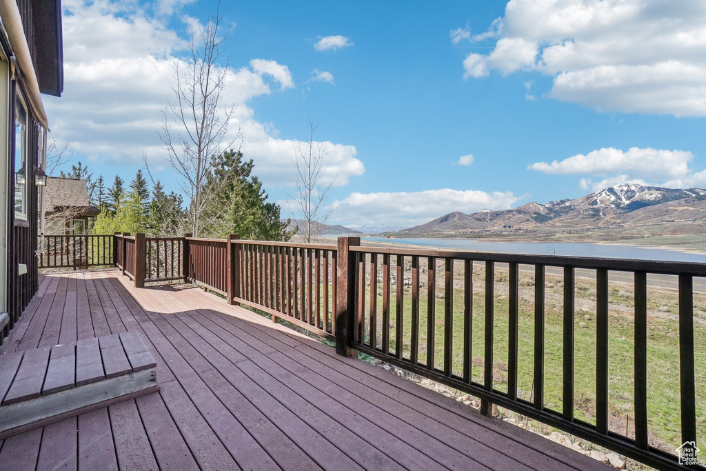 Deck featuring a water and mountain view and a lawn