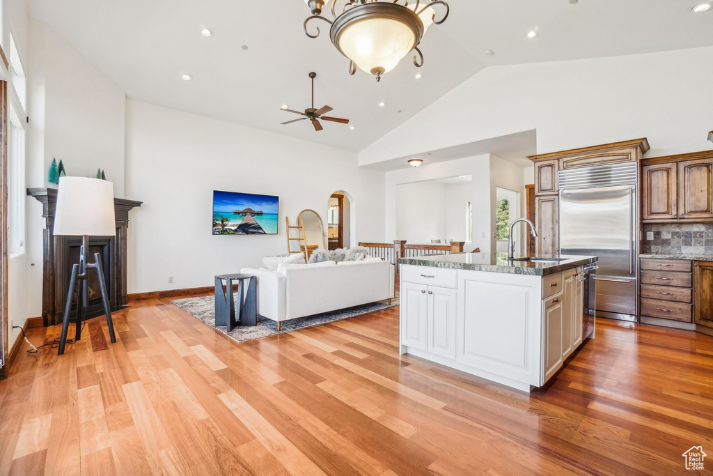 Kitchen featuring a sink, stainless steel built in refrigerator, light wood finished floors, ceiling fan, and open floor plan