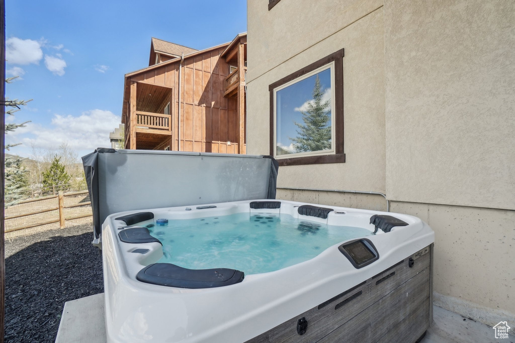 Exterior space with a hot tub, fence, and stucco siding